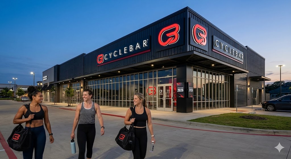 CycleBar Prices 2026: Memberships, Class Packs & Shoe Fees. Exterior of a modern CycleBar studio at dusk, featuring their signature red, white, and black branding.